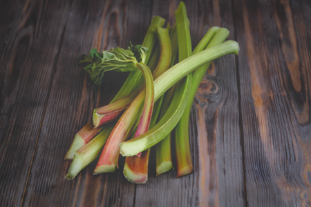 Stems of fresh young rhubarb Ingredients for food recipes healthy diet detox organic food vegetables on wooden background, low key copy space place for text top view soft selective focusの写真素材