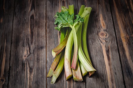Stems of fresh young rhubarb Ingredients for food recipes healthy diet detox organic food vegetables on wooden background, low key copy space place for text top view soft selective focusの写真素材