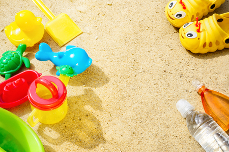 Beach Summer Sun Sand Kids Toys and bottle water slippers and Sunscreen concept of childrens leisure tourism entertainment games Skin Protection SPF UVA UVB radiation safety from Melanoma Cancer.の写真素材