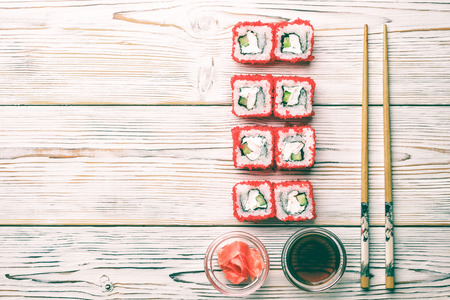 Set of sushi rolls of fresh shrimps cucumber avocado Tobiko caviar and Philadelphia cheese Asian food on white background with pickled fermented ginger and horseradish wasabi chopsticks.の写真素材