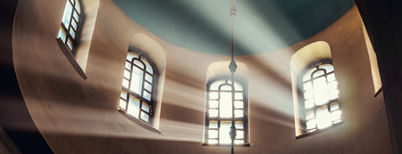 Sun rays make their way through the high vaulted arched window under dome in church temple Concept religion enlightenment light and darkの写真素材