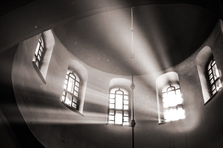 Sun rays make their way through the high vaulted arched window under dome in church temple Concept religion enlightenment light and darkの写真素材