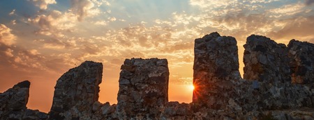 Fortress wall on mountain view of sunset on sea sun rays through clouds. Holiday vacation travel seascape Toned landscape wide angleの写真素材