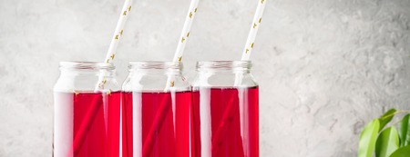 Beverage compote of red berries black currant cherries blueberries in cocktail jars with straws...