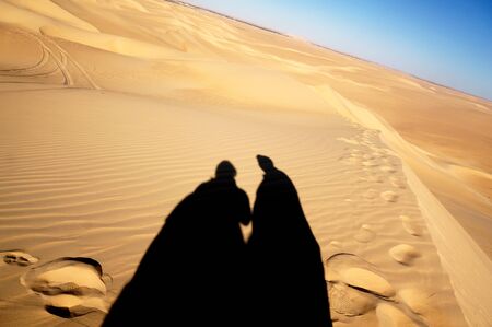 shadows of 2 persons on the sandの写真素材