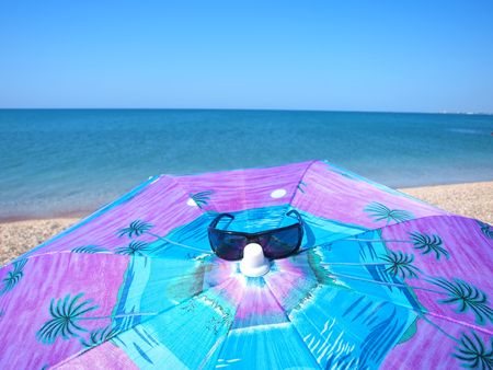 Sunglasses and sunshade on the summer beach. Evpatoria, Crimea, Ukraine    の写真素材