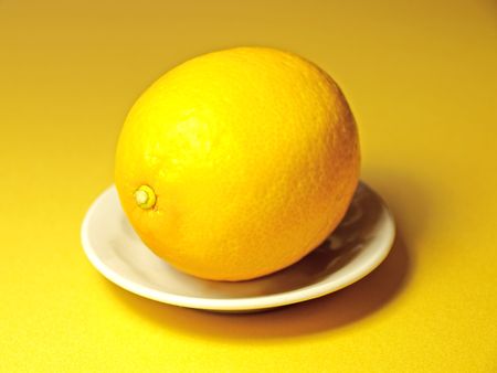Lemon on a small plate on yellow background の写真素材