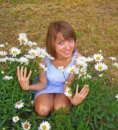 Blonde smiling girl with a lot of camomiles in her handsの写真素材