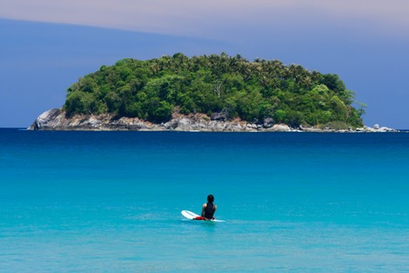 Surfer sitting on surfboard in water at the beach. Kata Beach, Phuket, Thailand.の写真素材
