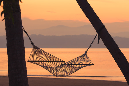 Fabric hammock against mountain and sea at sunrise background. Soft focusの写真素材