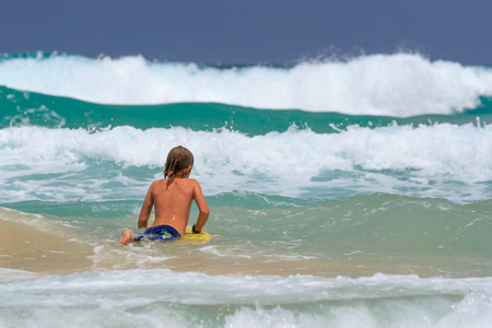 Young Surfer with surfboard going to the sea at surf spot.の写真素材