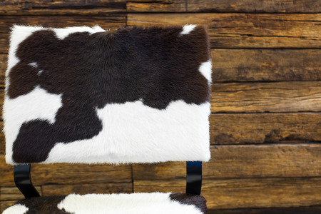 Cow skin chair  and old wood wall background.の写真素材