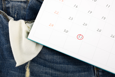 Jeans with empty pocket and calendar with a last day of the month.の写真素材
