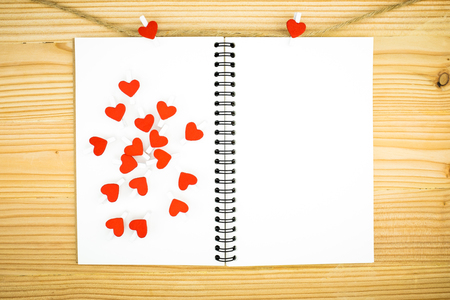 Red heart shape wooden clip and notebook on wooden table background.の写真素材