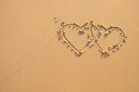 Two hearts drawn in the sand at the beach.の写真素材