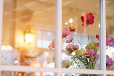 Colorful decoration artificial flower in window. Vintage color.の写真素材