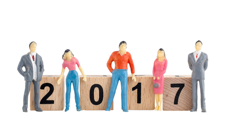 Miniature people with 2017 on wooden cubes isolated on white background, new year concept.