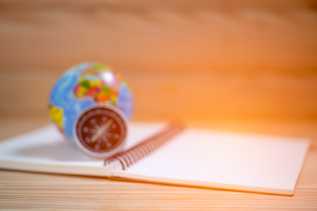 Blurred image of compass, orb and note book on wooden table.の写真素材