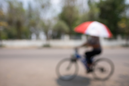Blurred image of Man with umbrella on a bike.の写真素材