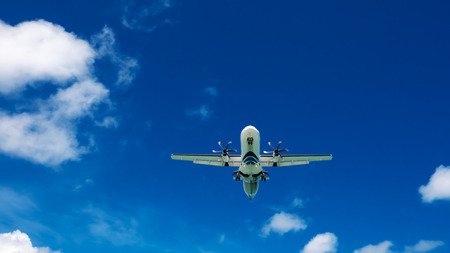Airplane flying in a blue sky with clouds.