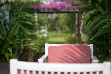 Red mattress on wooden chair against green garden background.の写真素材