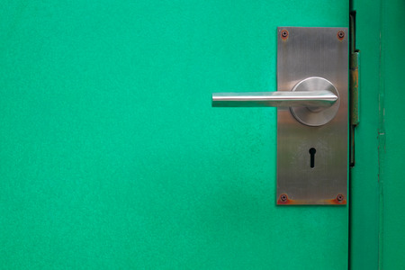 Old metal door handle on green steel door.の写真素材