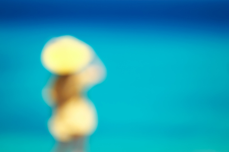 Blurred image of young girl in a yellow dress with sea background.