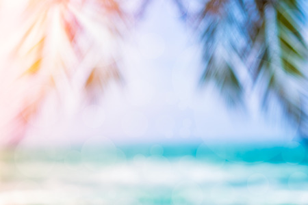 Blurred image of sea and coconut palm tree with bokeh and sun rays. Concept of beach in summer.の写真素材