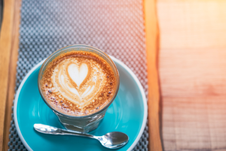 Cup of hot latte art coffee on wooden table.の写真素材