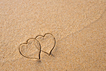 Two hearts drawn in the sand at the beach.の写真素材