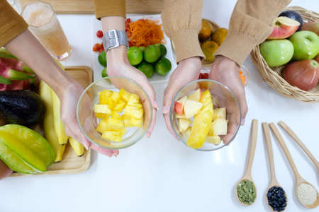 Top view of the couple's hand holding the fruit bowl and there are many fruits on the table. Food...