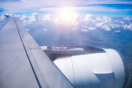 window view of airplane wing and engine in flight with clouds on sky background.の写真素材