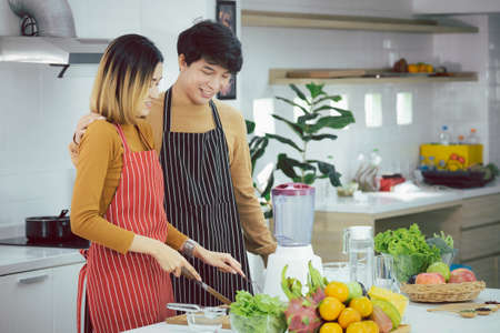 Asian young couple preparing a meal chopping vegetables in kitchen at home, healthy lifestyle.の写真素材