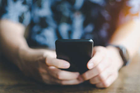 Man with hawaii shirt using mobile smart phone. Close up.の写真素材