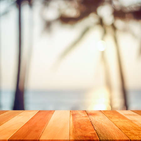 Wood plank with blurred sea and coconut tree background at sunset time. Concept of beach in summer.の写真素材
