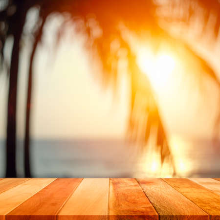 Wood plank with blurred sea and coconut tree background at sunset time. Concept of beach in summer.の写真素材