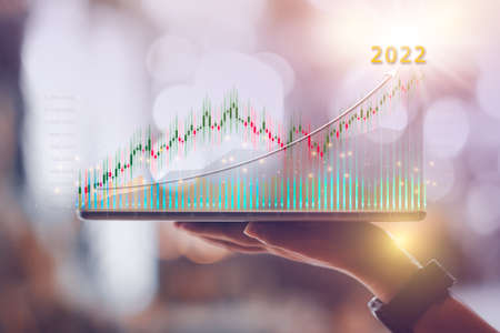 Woman hand showing virtual hologram stock from tablet,2022 business growth concept,Stock market graph or forex trading chart,Planning and strategy,Progress or success,Digital asset,Trader or investor.の写真素材