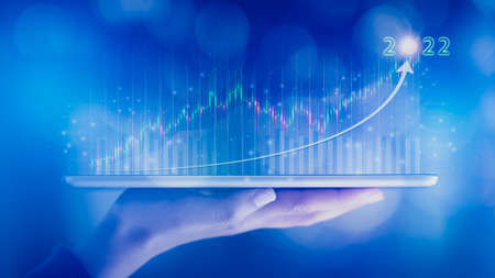 Woman hand showing virtual hologram stock from tablet,2022 business growth concept,Stock market graph or forex trading chart,Planning and strategy,Progress or success,Digital asset,Trader or investor.の写真素材