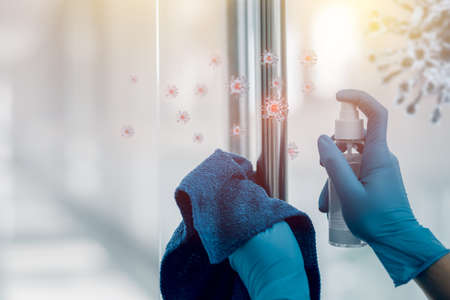 Hand in gloves wipe cleaning door handle with alcohol spray to prevent the spread of coronavirus COVID-19. Healthcare and disinfection concept.の写真素材