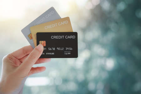Woman hand holding various credit cards on natural bokeh background.の写真素材
