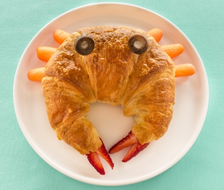 Croissant made into a crab using strawberries, carrots, mini marshmallows and sliced olivesの写真素材