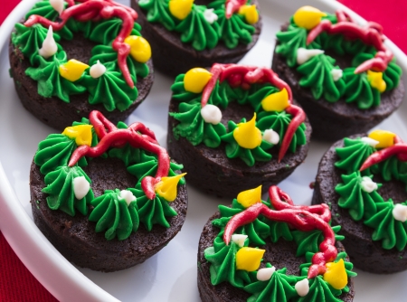Group of brownies with wreath icing decoration on red tableclothの写真素材