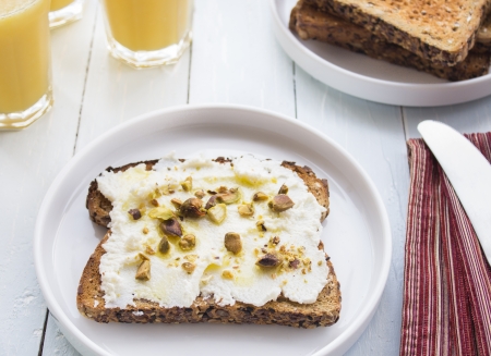 Ricotta spread on rustic toast, drizzled with olive oil and sprinkled with crushed pistachios