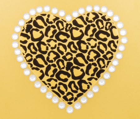 Black and gold animal print heart surrounded by white rhinestones on gold backgroundの写真素材