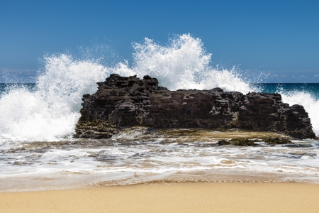 Dramatic splash against a large rock at the shore of Sandy Beach on Oahu, Hawaiiの写真素材