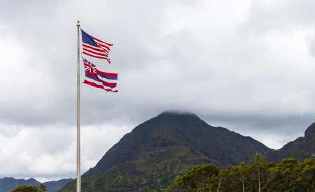 The Hawaiian and American flags flying high in front of the Koolau Mountains on Oahu, Hawaiiの写真素材