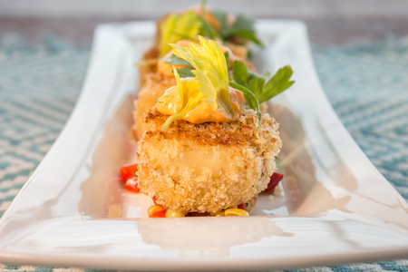 Breaded crab cakes served on top of corn relish and topped with sauce