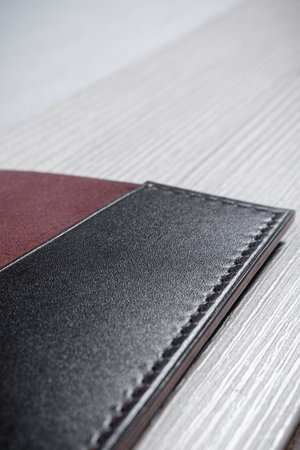 Leather passport cover lies on a geometric background consisting of brown and gray triangles with a...