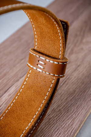 Detail of an orange leather belt lying on a brown tree close up
