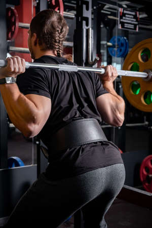 The athlete lifts a heavy barbell on his shouldersの写真素材